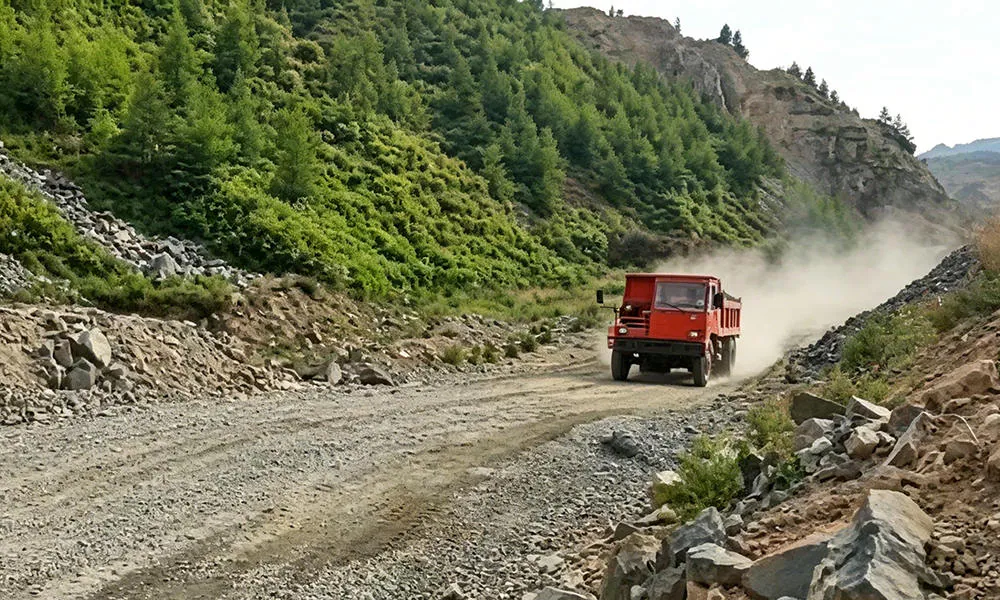 A red mining truck on a rough, dusty outdoor road.