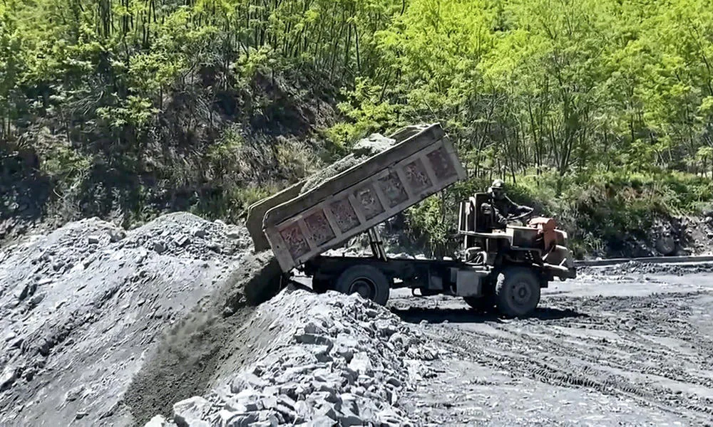 A dump truck discharging aggregate on an outdoor site.