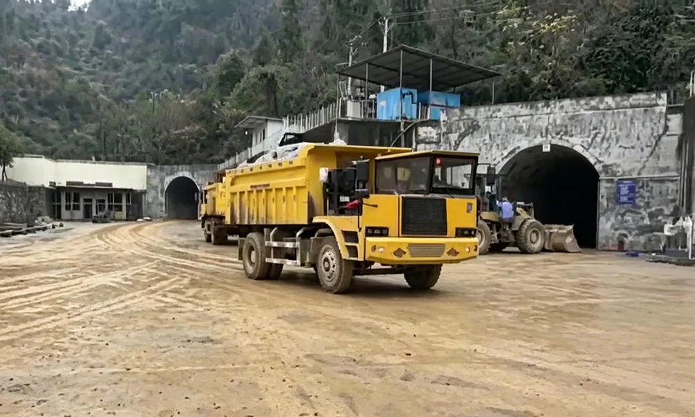 A yellow dump truck near a tunnel entrance.