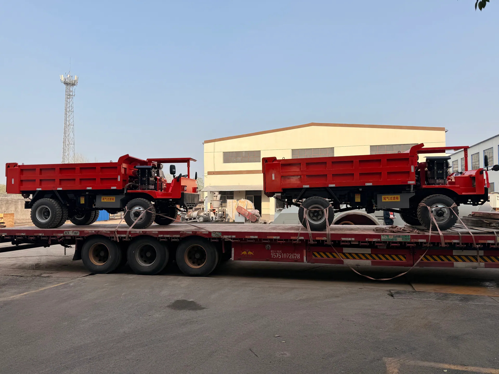 Mining vehicles positioned on flatbed transport outdoors.
